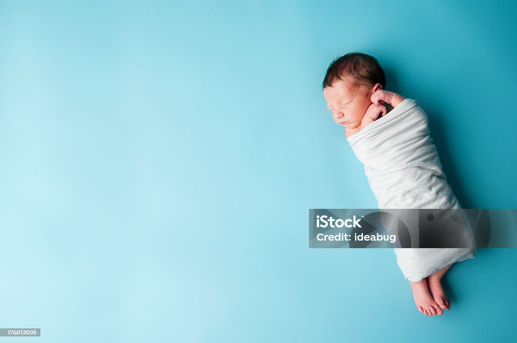 Newborn Baby Boy Sleeping Color photo of a newborn baby boy wrapped up in a blanket and sleeping peacefully on a teal background. Room for text on left. Baby - Human Age Stock Photo