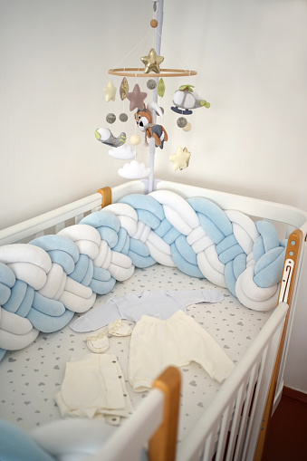 Cot for a newborn with clothes and toys.