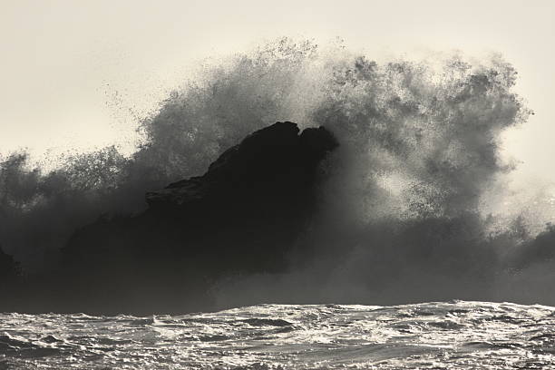 Ocean Wave Crashes Rock Coast Sunrise backlit ocean surf surrounding rock silhouette.  Mavericks Beach, Half Moon Bay, California, 2009. mavericks california stock pictures, royalty-free photos & images