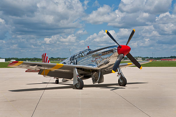 p51 mustang WWll fighter plane a vintage p51 mustang restored and done up all in chrome sits on an airport taxi way on a cloudy summer afternoon p51 mustang stock pictures, royalty-free photos & images
