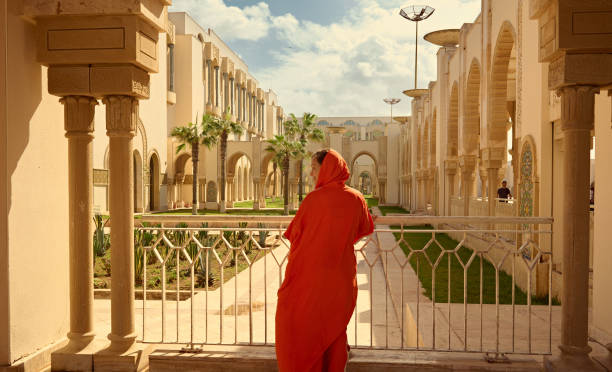 vista trasera de una turista vestida con ropa tradicional marroquí auténtica, visitando y admirando la mezquita hassan ii - casablanca moroccan culture style islam fotografías e imágenes de stock