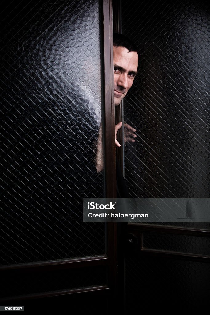Sournoise homme Regarder à travers des portes en verre - Photo de 30-34 ans libre de droits