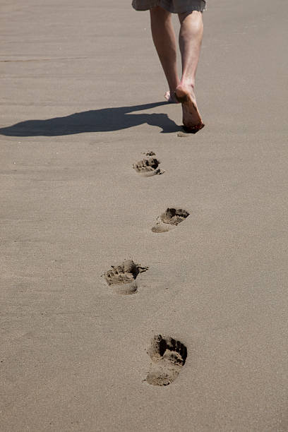 Vertical high angle closeup photo of two sets of footprints walking close together on the sand at Wategos Beach, Byron Bay, north coast NSW.