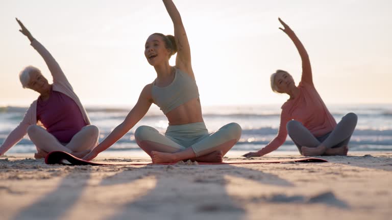 Beach yoga class, sunset and instructor coaching mindfulness pose, stretching and morning workout. Sun flare, nature sunshine and spiritual people learning pilates, training and coach teaching group