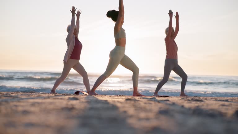 Beach yoga class, sunset and meditation coach teaching breathing, mindfulness and spiritual chakra, aura or soul healing. Ocean waves, relax yogi and personal trainer coaching learning pilates group