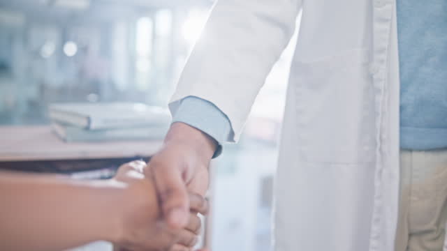 Person, doctor and handshake in meeting, partnership or deal agreement together at the hospital. Closeup of medical or healthcare professional shaking hands in greeting, introduction or thank you