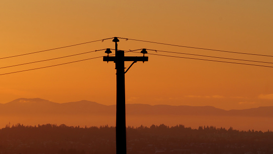 Silhouette of an electric wire pole during a beautiful sunset over Metro Vancouver in British Columbia, Canada.