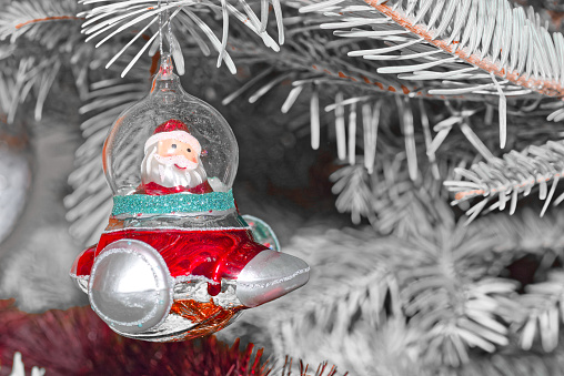 Close-up of red spaceship with Santa Claus hanging on Cristmas tree agains white branches