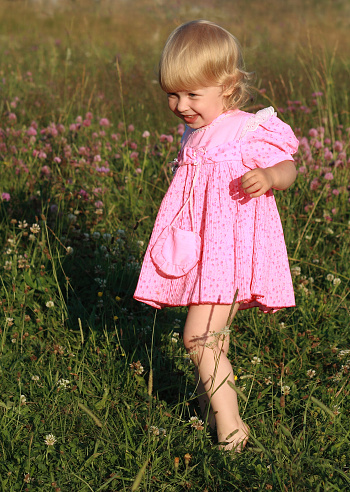 A cheerful girl with Downs syndrome on the green meadows at the sunset
