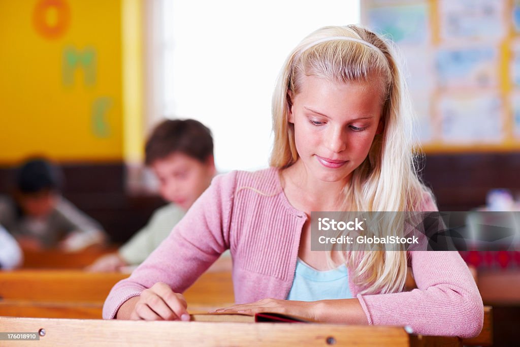 Linda niña en edad escolar lectura en montaje tipo aula - Foto de stock de 10-11 años libre de derechos