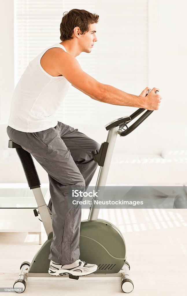 Giovane uomo allenamento su una cyclette - Foto stock royalty-free di 25-29 anni