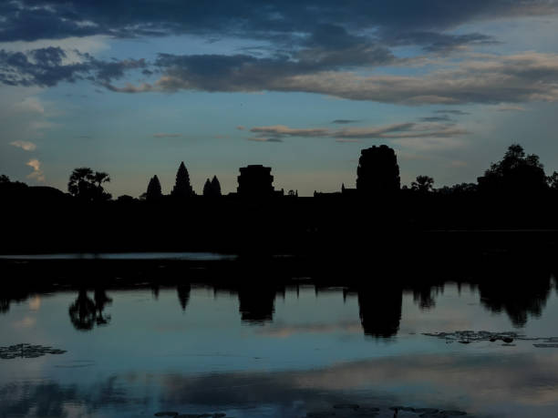 Ankor Wat temples in silhouette reflected in the water at late sunset.