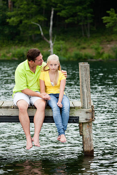 istock Father Comforting his sad Daughter on a Dock 176019484