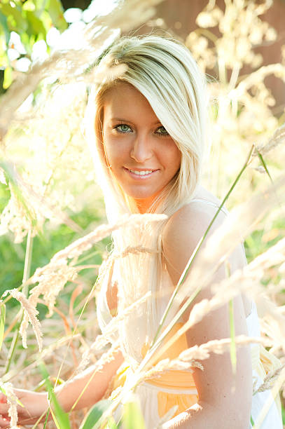 warm toned blond woman in field rural setting stock photo