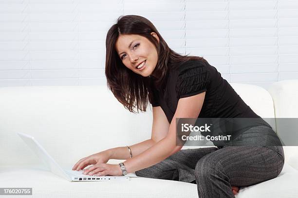 Foto de Jovem Mulher Sentada No Sofá Com Laptop e mais fotos de stock de Camiseta - Camiseta, Mulheres, Relaxamento