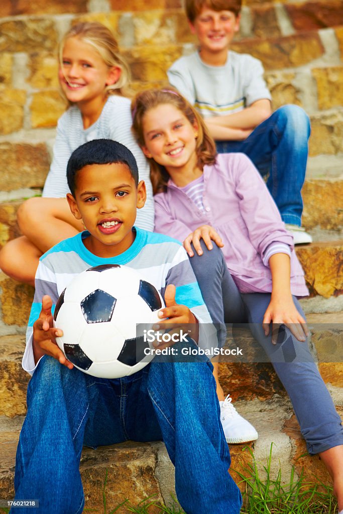Happy boy holding Fußball und sitzt mit seinen Freunden - Lizenzfrei 10-11 Jahre Stock-Foto