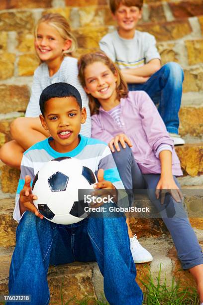 Szczęśliwy Chłopiec Trzymając Piłki Nożnej I Siedzi Z Kolegami - zdjęcia stockowe i więcej obrazów 10-11 lat