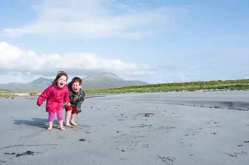 A 4 year old boy and a 2 year old girl having fun on the beach. South Uist, Western Isles, Scotland.