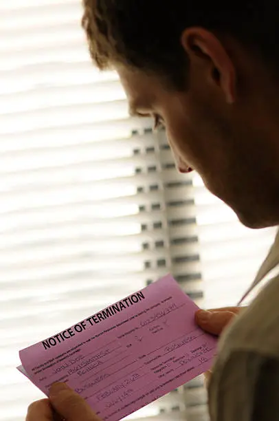 A man is reading the Notice of Termination he has received. Focus on the pink slip. Shot at Toronto Echucalypse 2009.