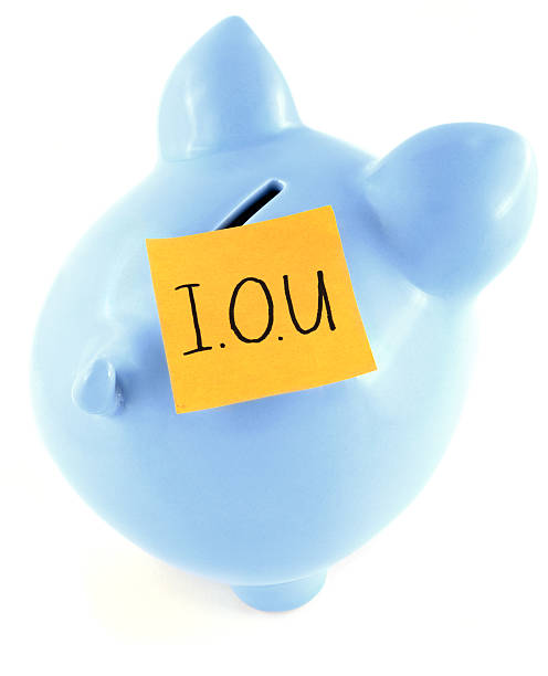 I owe you Blue ceramic piggy bank with orange IOU note stuck to the coin slot. Visible pigment detail in the piggy bank glaze. ira approved bullion stock pictures, royalty-free photos & images