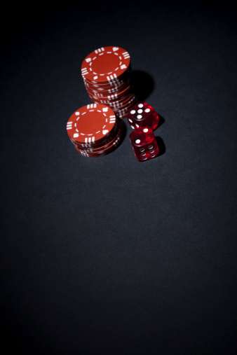 Stacks of red playing chips and dice - spotlit.