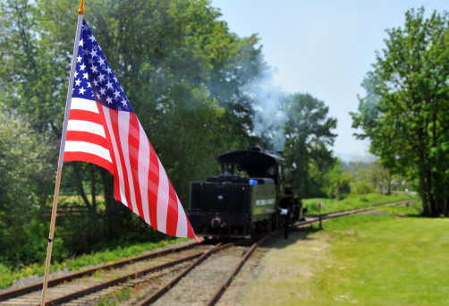Steam train in background with USA flag in foreground.