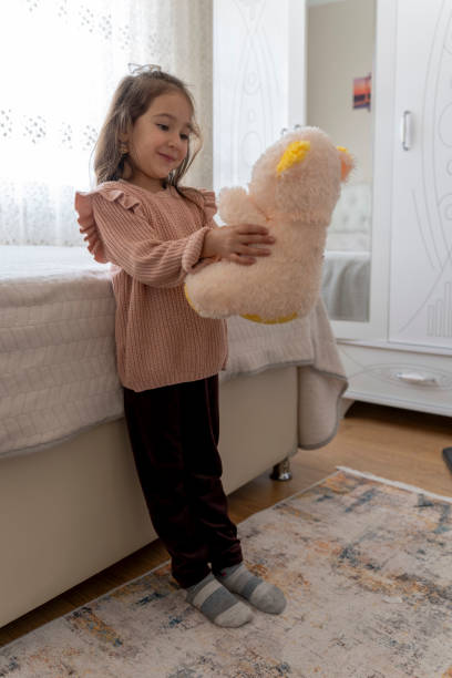 Girl playing with teddy bear in nursery.