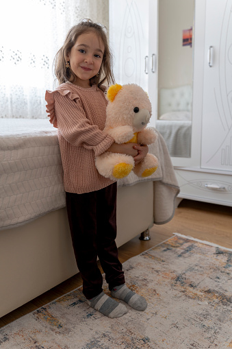 Girl playing with teddy bear in nursery.