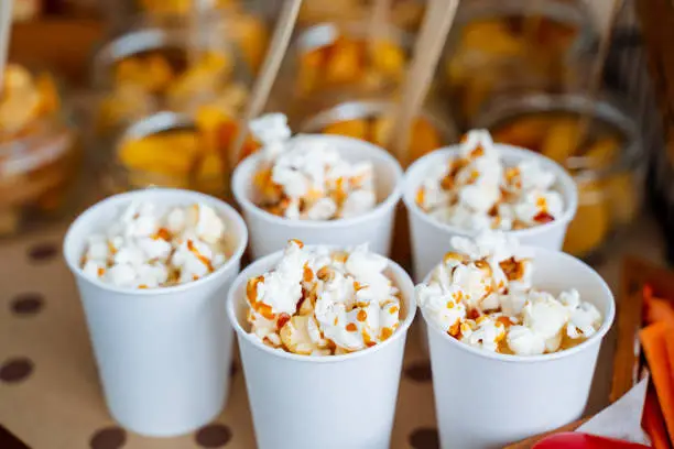 Photo of Cups of popcorn with caramel. Crispy sweetness. A bucket of popcorn for a trip to the movies. Five servings of delicious popcorn with caramel