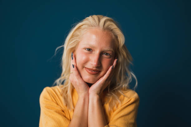 istock Cheerful young woman with hands on her face against blue background 1760291722