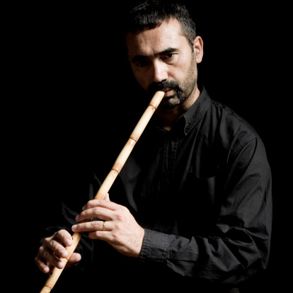 Man playing flute on black background