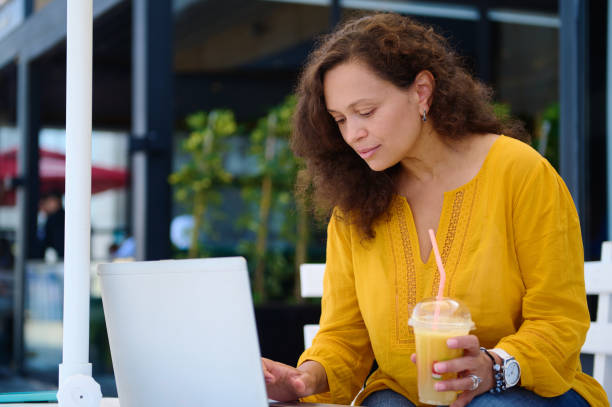Attractive woman in casual clothes, working online on laptop from a modern outdoor cafe. People. Business. Lifestyle