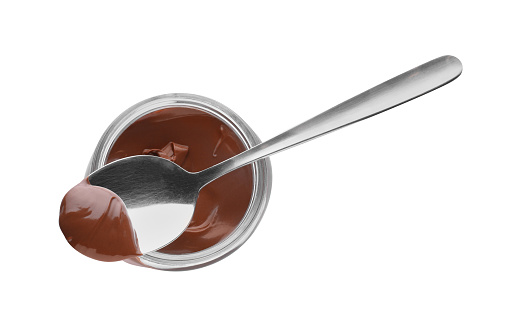 Jar and spoon with tasty chocolate paste isolated on white, top view