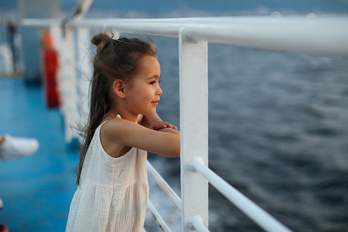 Little girl learning out of the stern of a ship.