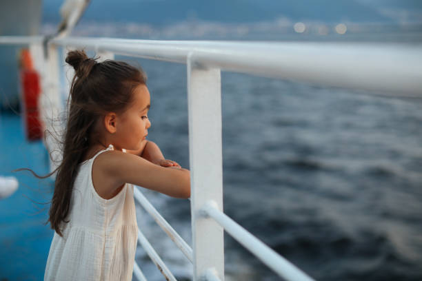 Little girl is on a ship, boat or ferry. Little girl learning out of the stern of a ship. ferry deck girls stock pictures, royalty-free photos & images