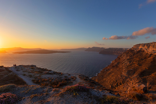 Santorini sunset over the Caldera, on the right the coast of the island and on the left the sea and the setting sun.