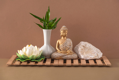 Buddha statue, lotus flower, and bamboo branch. The concept of SPA and healthy lifestyle.