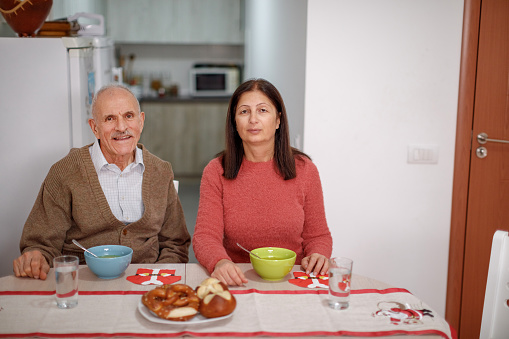 Two people enjoying together eating modest meal at kitchen table