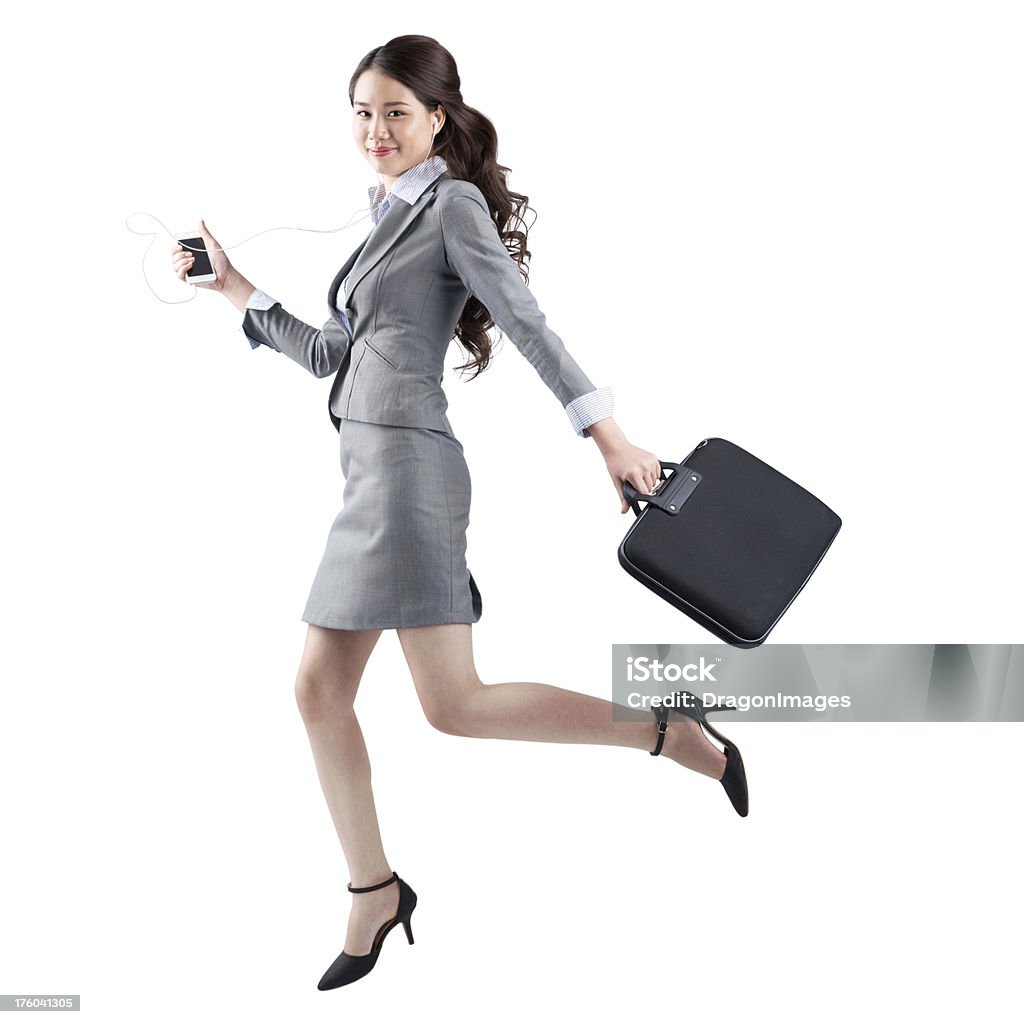 Business in a hurry Isolated portrait of a modern businesswoman running with a briefcase and mp3 at work Adult Stock Photo