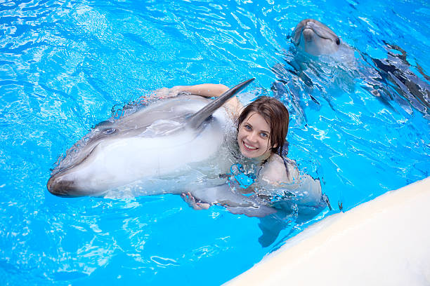 istock young woman swims with a dolphin in the pool 176041771
