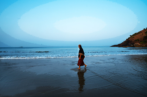 02-22-2019    Goa, India   Monk ewalking arly morning on the beach on beach at  southern India (Goa). He walkinf barefoot and in traditional clothing!