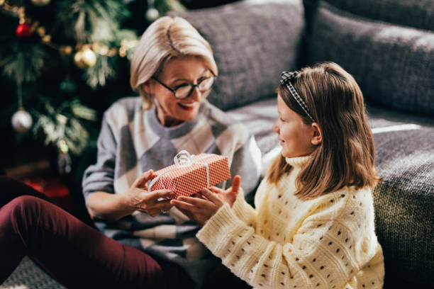 uśmiechnięta starsza kobieta daje prezent świąteczny swojej wnuczce - grandmother giving gift child zdjęcia i obrazy z banku zdjęć