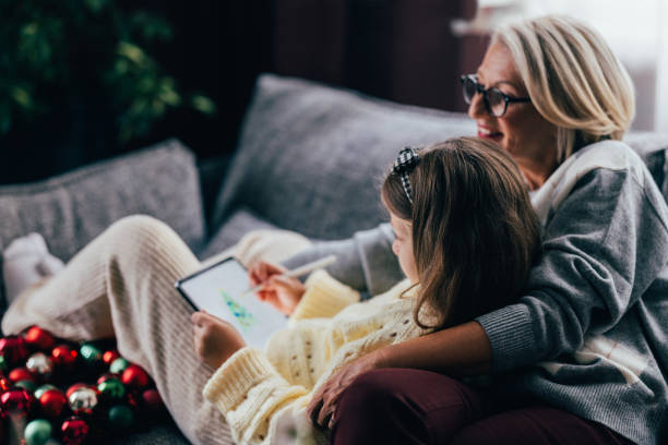 istock Festive Bonding: Granddaughter Draws a Digital Christmas Tree with Grandma 1760419486