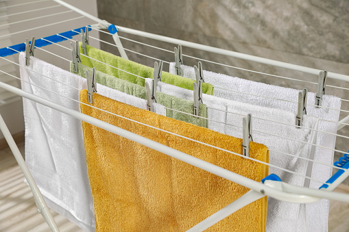 Clean terry towels hanging on drying rack indoors