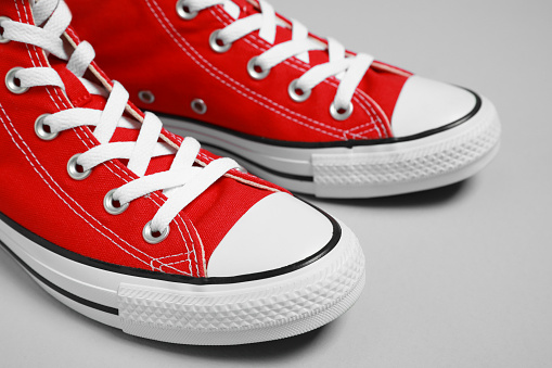 Pair of new stylish red sneakers on light grey background, closeup