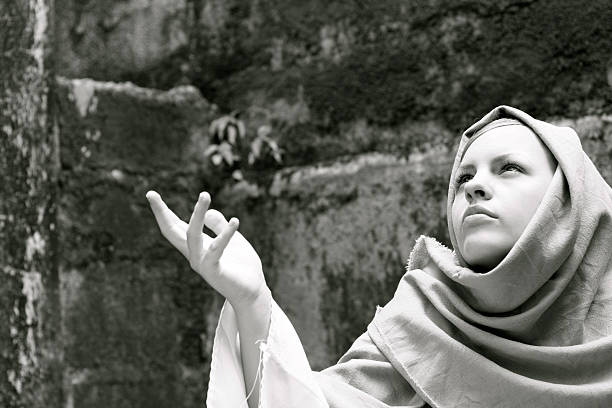 A woman dressed in Biblical clothing raising her hand as if in prayer or to beg. Could be the Virgin Mary.