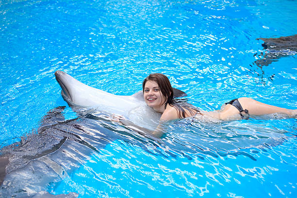 istock young woman swims with a dolphin in the pool 176043102