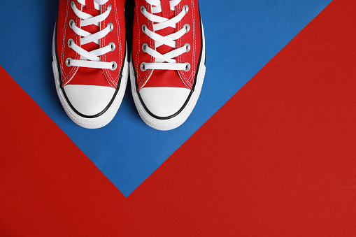 Pair of new stylish red sneakers on colorful background, flat lay. Space for text