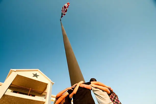 Photo of Teenagers Praying Around a Flag Pole