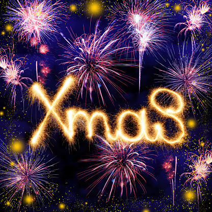 Xmas sign made of sparkler trace on a night blue sky background with lots of beautiful fireworks